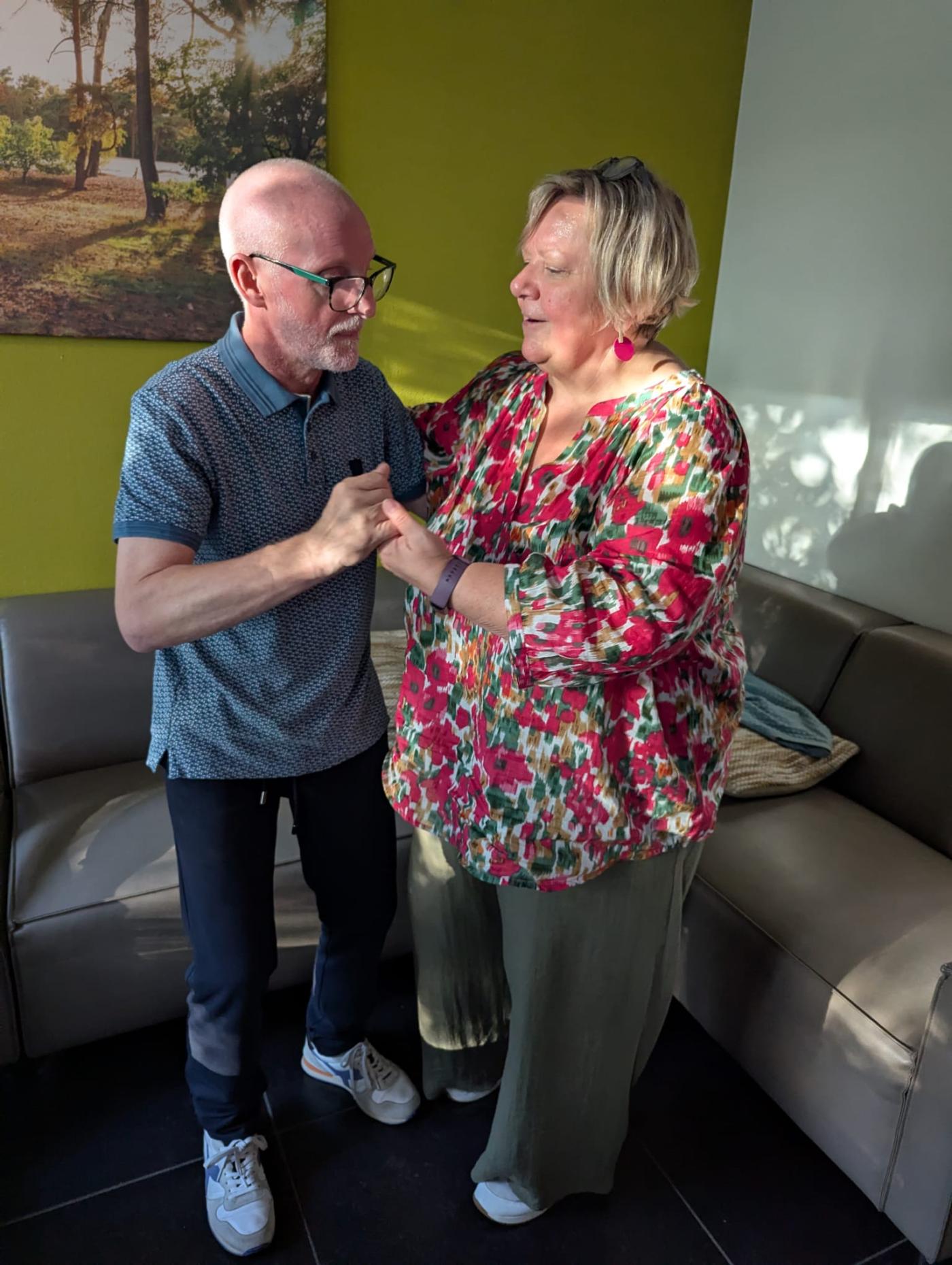 Ingrid en Marc dansen en zingen in de woonkamer